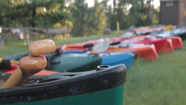 A picture of counes and kayaks getting ready for a trip down the river. 