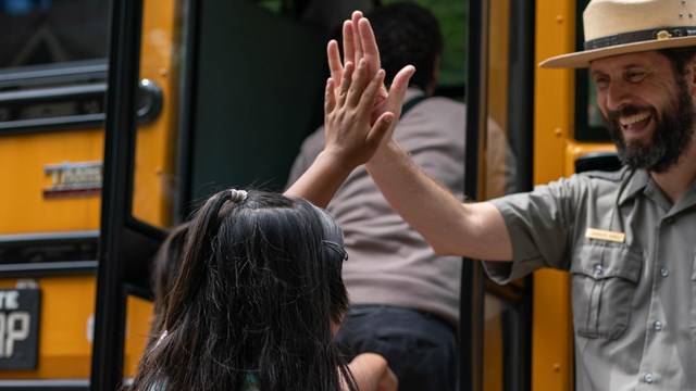 ranger gives student high five outside school bus