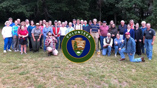 Group photo with dozens of people. Centered is the round NPS Volunteer logo