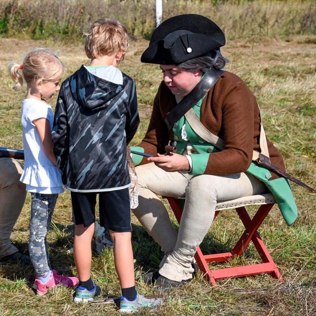 two kids talking to two adults dressed as soldiers