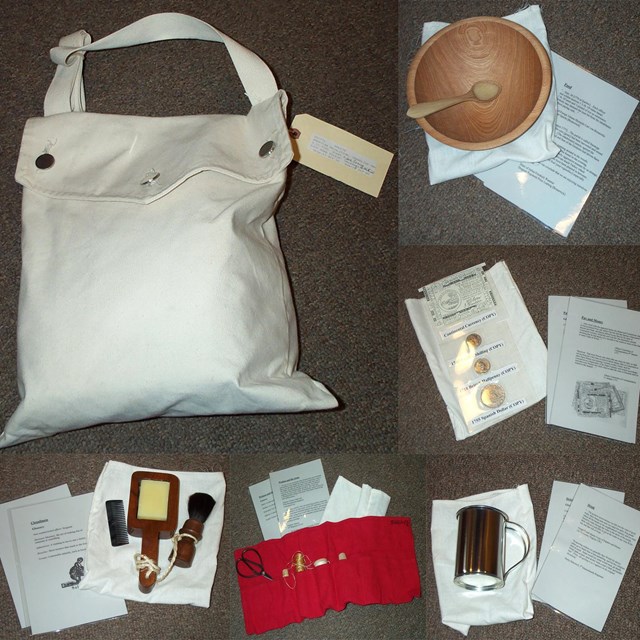 A white bag, wooden bowl and spoon, coins, cup, sewing kit, brushes, and paper lay on the ground.