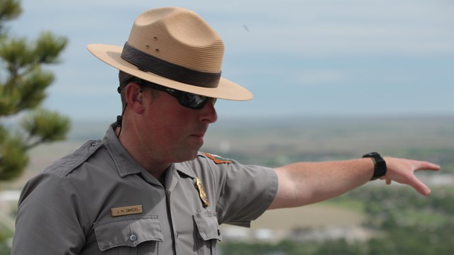 A park ranger points to a far off location.