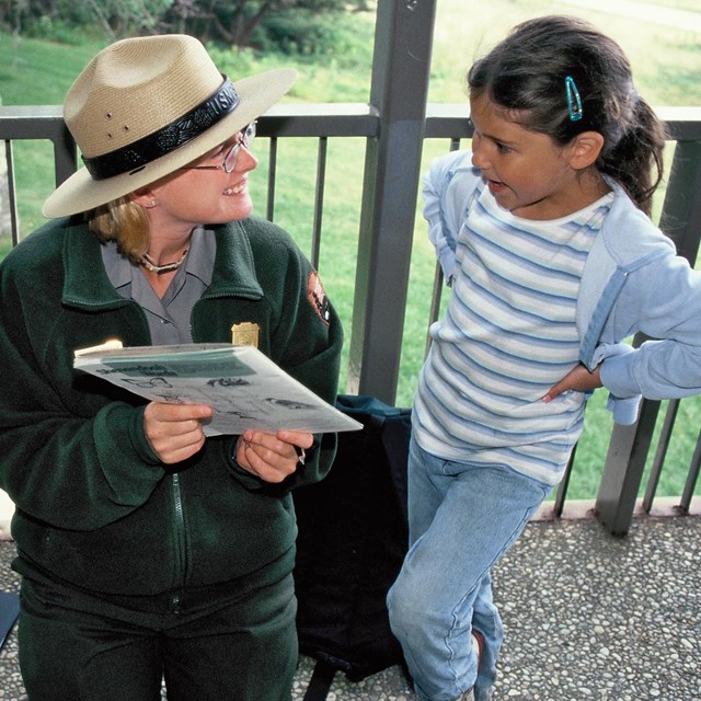 A Ranger reviewing a junior ranger booklet with a your girl.