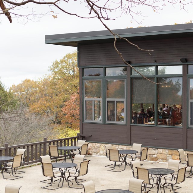 An outdoor seating area adjacent to an indoor restaurant with a view of the valley below.