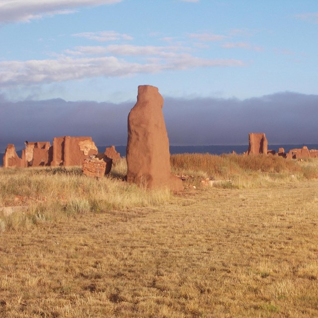 Ruins of fort walls lit by the sun against a darker sky