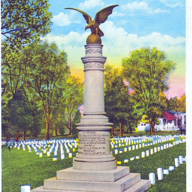 A postcard with a grey concrete column with a brass eagle on a brass ball on top of it. The column s