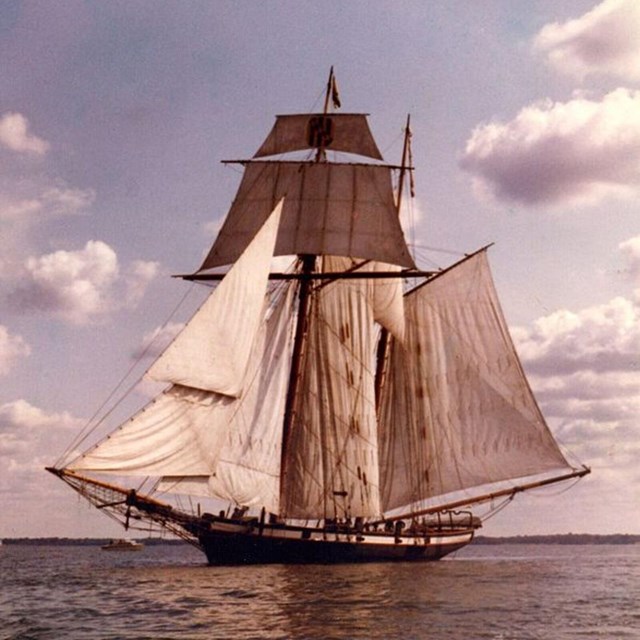 A ship with a large sail on the water.