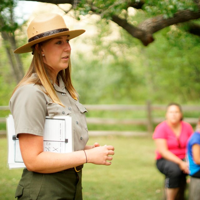 A ranger stands in front of a group of seated park visitors