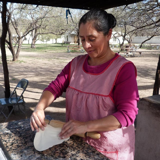 woman in apron making tortilla