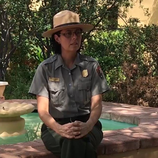 park ranger sitting next to a fountain in a garden