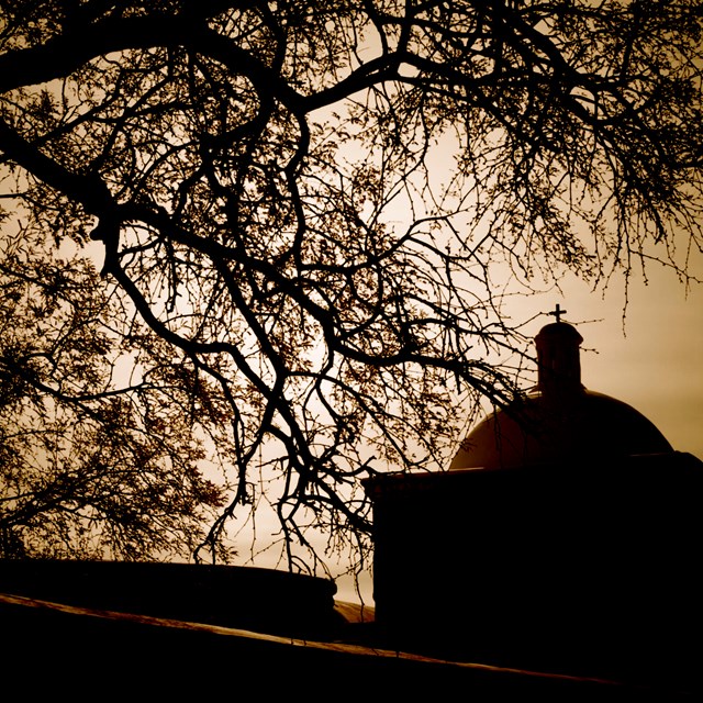 sepia toned sky with silhouette of church and trees