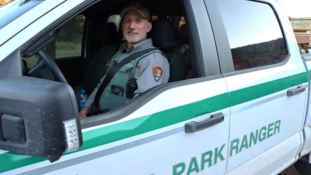 A ranger sitting in a green-striped white pick-up