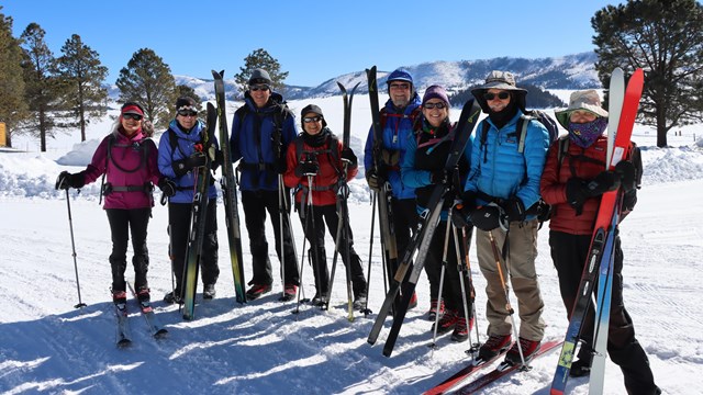 Several skiers bunch together for a group photo in a snowy landscape.