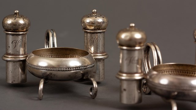 A pair of individual silver salt cellars and casters monogrammed with a V.