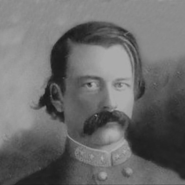 A black and white bust image of Confederate general with long black hair and mustache.