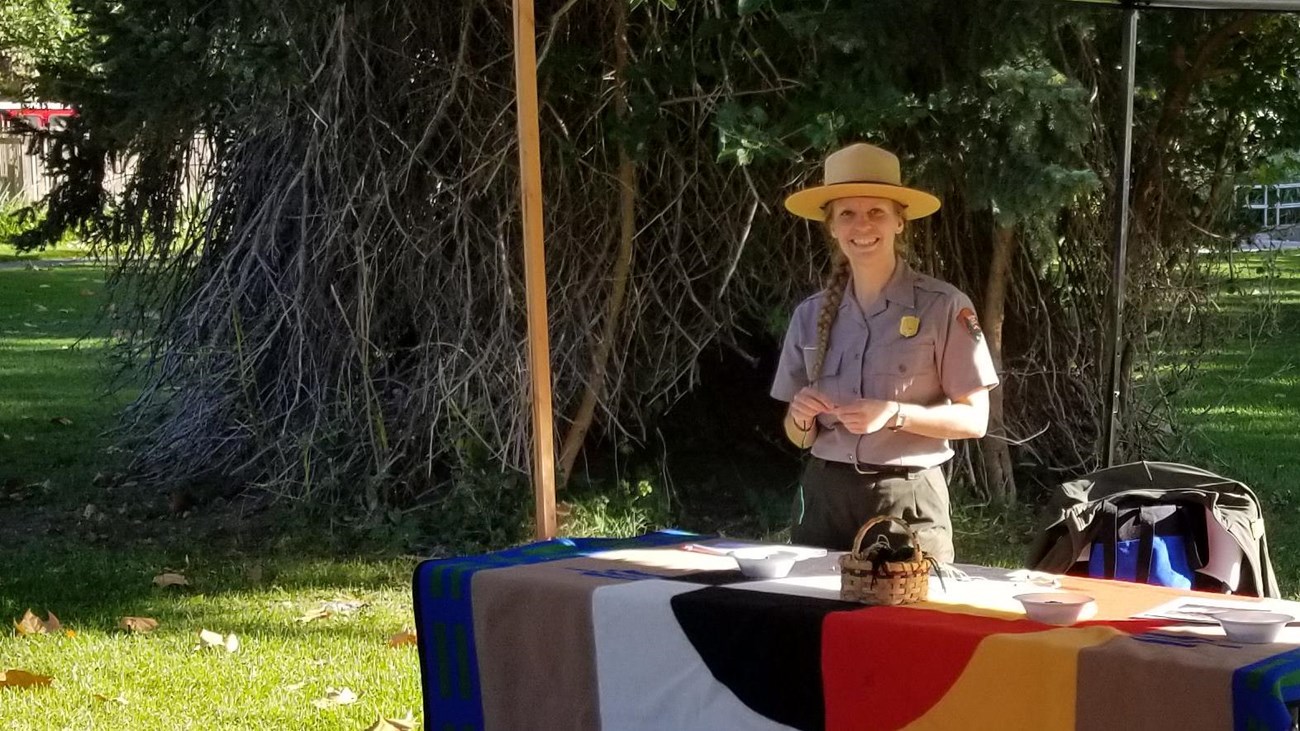A ranger stands at a table at an outdoor event