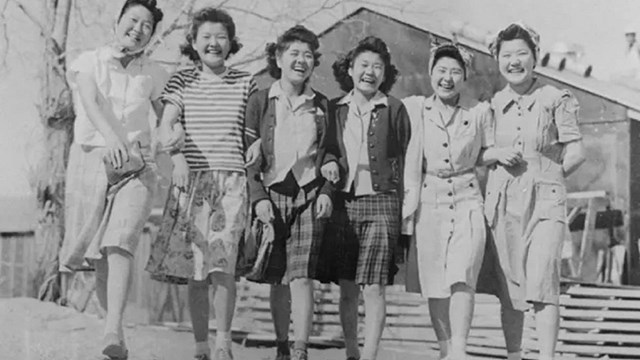 Six Japanese American women walk in Manzanar camp in 1940s