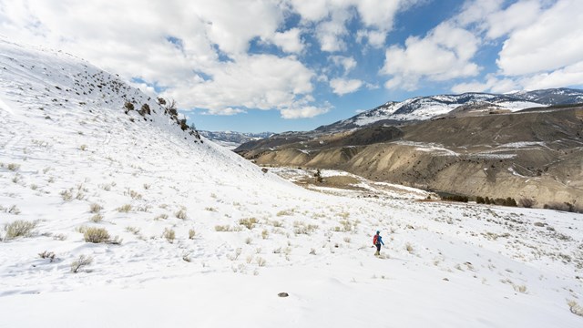 a person hiking through snow on a partly cloudy spring day