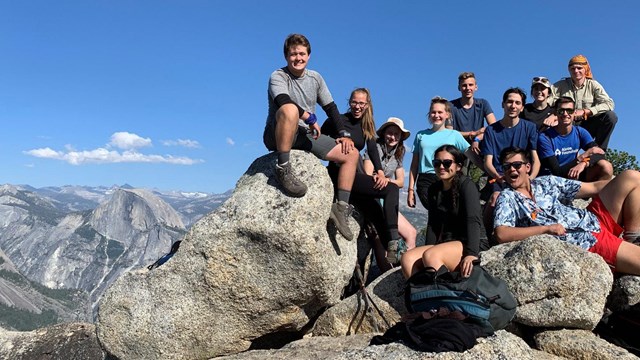 Students sitting on granite rocks with view of Half Dome