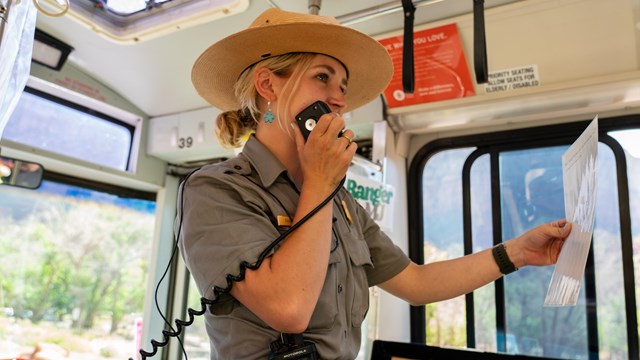 A ranger speaks into a bus speaker 