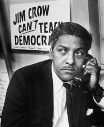 Mr. Rustin on the phone with &#39;Jim Crow Can&#39;t Teach Democracy&#39; sign behind him