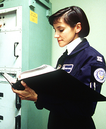 A woman in uniform holds a large black binder