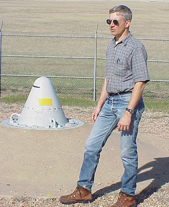 Man stands next to a metal cone in the ground