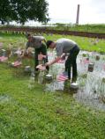 Rangers Kathryn Harrison and Matt Boswell placing flags on grave sites at the Chalmette National Cemetery.