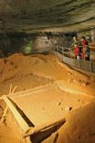 Park guide Jackie Wheet and two visitors look at the saltpeter leaching vats in the Rotunda, in Mammoth Cave.