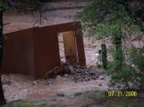 The well pump housing was displaced, battered, and half-buried by flooding. The pump house was originally located near a normally dry wash that flooded out of its banks.