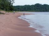 Two visitors walk barefoot along the mile long stretch of sand at Julian Bay Beach on Stockton Island.