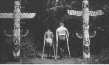 Two boys walk between two totem poles in approximately 1937 as part of the Maryland League for Crippled Children from Baltimore, MD stayed in Camp Greentop.