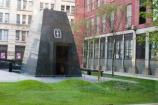 The outdoor memorial at African Burial Ground National Monument rises behind some of the mounds marking the reinterrment site of the human remains that were unearthed when the burial ground was rediscovered.