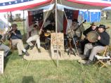 Several reenactors playing flute, fiddle, guitar, banjos and a large tambourine