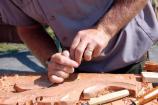 National Park Service carpenter John Pyndynkowski demonstrates traditional carving methods as he makes decorations for the transom of the replica tall ship Friendship of Salem