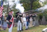 A group of re-enactors fire a volley in remembrance of the soldiers who died during the Battle of Pell's Point and are buried in the cemetery at St. Paul's Church National Historic Site