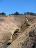 An excavator removes contaminated soil from an old Army landfill