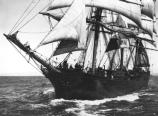 An 19th century vessel underway with some of her squaresails and staysails set.
