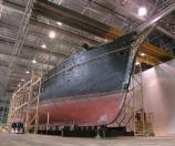 The Thayer is freshly positioned in the old seaplane hangar and the scaffolding is going up. For the next three years the hull would be encased in this wooden web. The scaffolding design was easily modified to meet the changing requirements as the job progressed. Note the distortion in the line of the keel. After the bulk of the outer planking had been removed the crew was able to settle this “hog” out of the keel.
