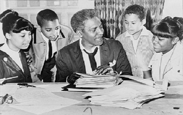 Bayard Rustin sitting with 4 children. Black and white photo