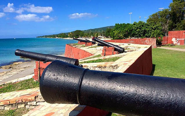 Cannons atop a red wall look over the blue ocean. Photo by N2theBlue CC BY-SA-4.0