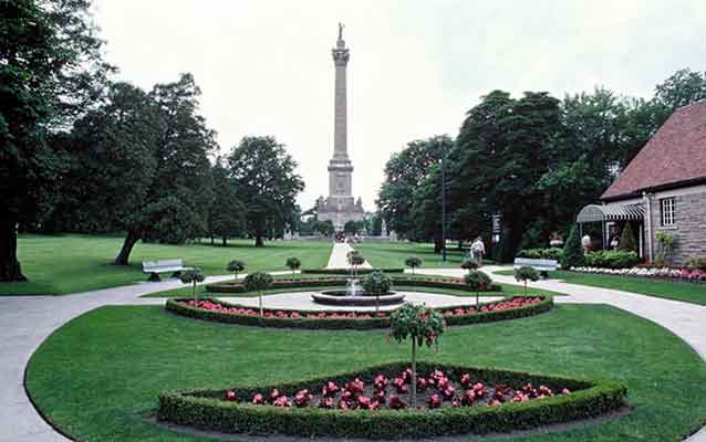 The yard at Queenston Heights. Circular yard with sidewalk and landscaping and a tall statue.