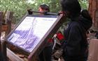 Two girls add a top railing to an outdoor exhibit
