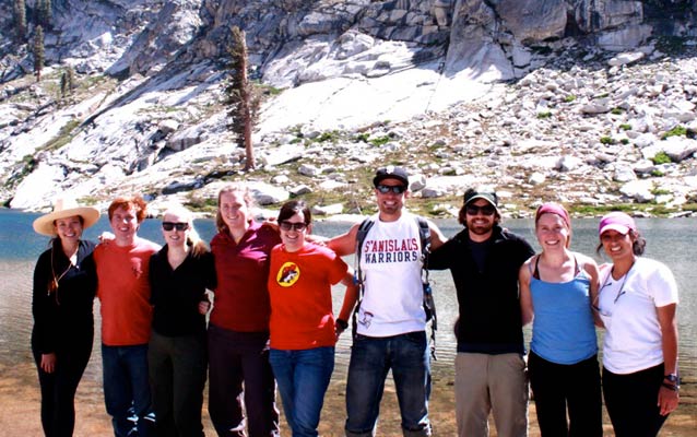 Interns stand smiling at the edge of a lake