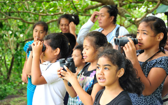 Photo of elementary students using binoculars to watch native birds.