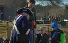 A reenactor brings the Revolutionary War to life for 2 young children and their dad.