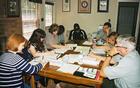 Park employees sit around a table in the administrative office and work on an assignment.
