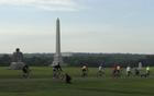 Bicycles ride past a series of stone monuments