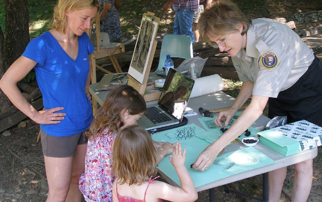 Artist in Residence, Kelly Adams, helps young park visitors with charcoal drawing techniques.