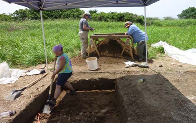Students and NPS archeologists excavating a unit